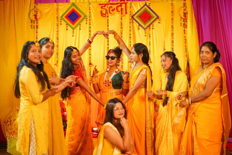 Joyful women in vibrant yellow celebrating a traditional Haldi ceremony.