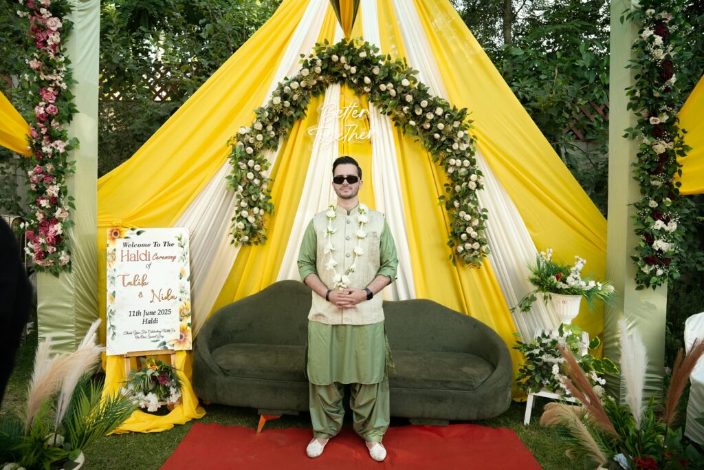 Joyful Haldi ceremony featuring a traditionally dressed groom amidst vibrant decor.
